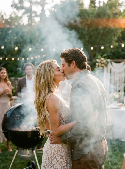 Backyard wedding kiss through a haze of barbecue smoke.