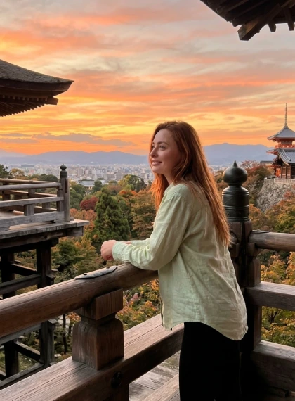 Naslonjena poza na leseni terasi Kiyomizu-dere: Panoramski pogled na Kyoto ob sončnem zahodu